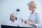 Female neurologist holding lamp, looking at male patient undergoing electroencephalogram