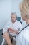 Female neurologist holding lamp near male patient undergoing electroencephalogram