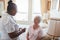 Female nurse giving medicine to senior patient at home