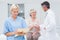 Female nurse making reports while doctor and patient shaking hands