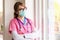 Female nurse wearing face mask while looking out to window