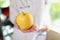 Female nutritionist shows ripe yellow apple on her hand close-up.