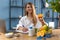 A female nutritionist smiles at the camera and holds a half of an orange, sitting at her desk in a white shirt.