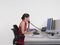 Female Office Worker Using Computer And Telephone At Desk