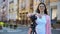 Female operator standing near camera with tripod on city street, production