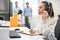 Female operator talking with client via headphones with microphone and writing notes to notebook in call center