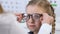 Female ophthalmologist choosing eyeglasses for smiling small girl, optical frame