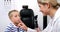 Female optometrist examining young patient with ophthalmoscope