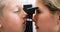 Female optometrist examining young patient with ophthalmoscope