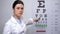 Female optometrist showing letters on eye chart, vision check up, health