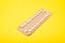 Female oral contraceptive pill blister on a yellow background background