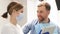 Female orthodontist advises a young man in the dental office, a doctor holding a tablet.