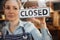Female Owner Of Small Business Turning Round Closed Sign In Shop Door