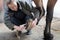 Female Owner In Stable Cleaning Feet Of Horse With Brush