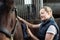 Female Owner In Stable Grooming Horse With Brush