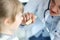 Female paediatrician examining little kid patient throat with wooden stick