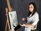 Female paint artist posing next to a easel and paints on an canvas, depicts a reverie
