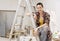 Female Painter Sitting On Ladder At Work Site