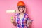 Female painter using roller for refurbishing color of pink wall indoors.smiling woman in business checkered shirt