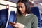 Female Passenger Sitting In Train Looking At Mobile Phone