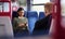 Female Passenger Sitting In Train Looking At Mobile Phone