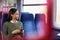 Female Passenger Sitting In Train Looking At Mobile Phone