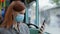 Female passenger wearing medical mask and gloves decontaminates a mobile phone with an antiseptic due to coronavirus