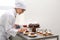 Female pastry chef decorating desserts with berries at table