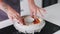 A female pastry chef puts orange jelly in a mold filled with cream