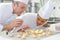 Female pastry intern putting topping on coconut macaron