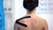 Female patient with applied Y-shaped tape on shoulder, alternative medicine