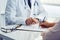 Female patient filling out medical document with doctor