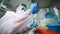 female PCR laboratory researcher in a protective medical suit, sterile mask, helmet, rubber gloves with a dispenser in