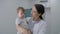 Female pediatrician holds little boy, looks at camera and smiles