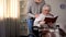 Female pensioner in eyeglasses reading book, young woman hugging grandmother