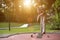 Female pensioner at a minigolf court hits a ball with an iron ra