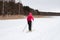 Female person exercising cross-country skiing on the frozen lake ice sheet in winter day.Active people outdoors. Scenic