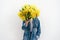 A female person hides her face behind a large bouquet of mimosa