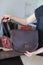 Female person with manicure keeping woman brown leather handbag.