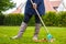 Female person raking green grass from brown leaves