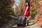 Female person in red dress walking under autumn trees