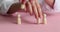 Female person swapping small wooden figures on pink table