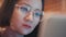 Female person working as video game developer. Close-up freelancer wearing glasses reflecting screen of laptop with