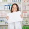 Female Pharmacist Holding Blank Paper At Pharmacy