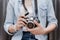 Female photographer holding mirrorless digital camera in her hands.Teenager carrying small camera for travel