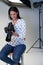 Female Photographer In Studio For Photo Shoot With Camera And Lighting Equipment