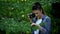 Female photographer taking photo of green tree leaves in park, naturalist hobby