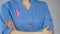 Female physician with pink ribbon in blue uniform, breast cancer awareness