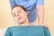 Female physiotherapist or a chiropractor adjusting patients neck. Physiotherapy, rehabilitation concept. Top view cropped shot.
