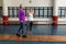 Female physiotherapist helping disabled senior woman walk with parallel bars in sports center